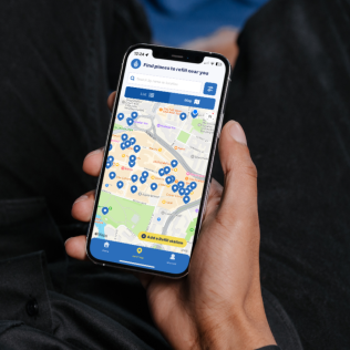 A hand holding a smartphone that shows the Refill app.