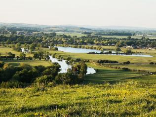 A beautiful green view of fields, trees, and a meandering river from Wittenham Clumps in Oxfordshire.