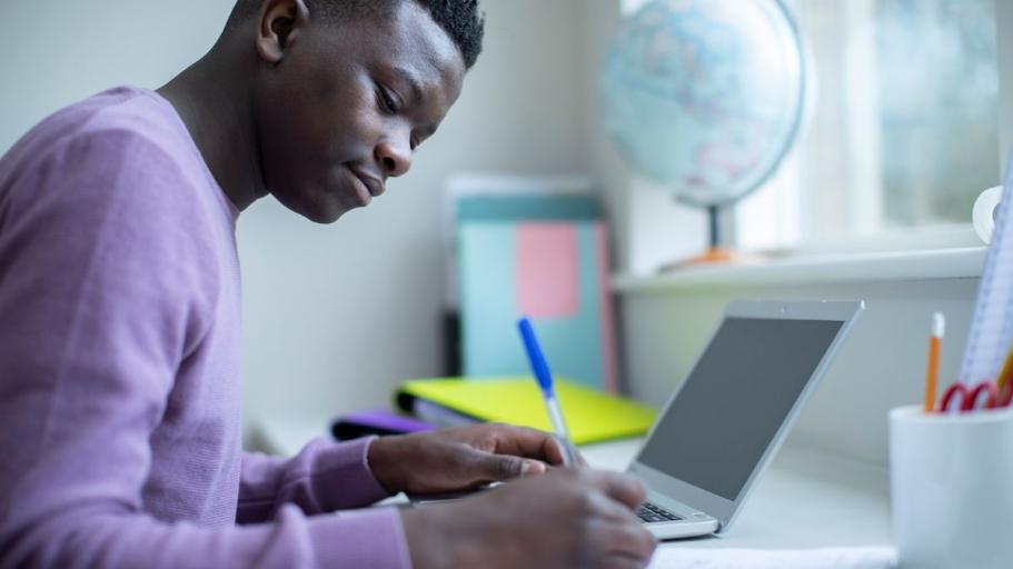 Someone writing next to a laptop