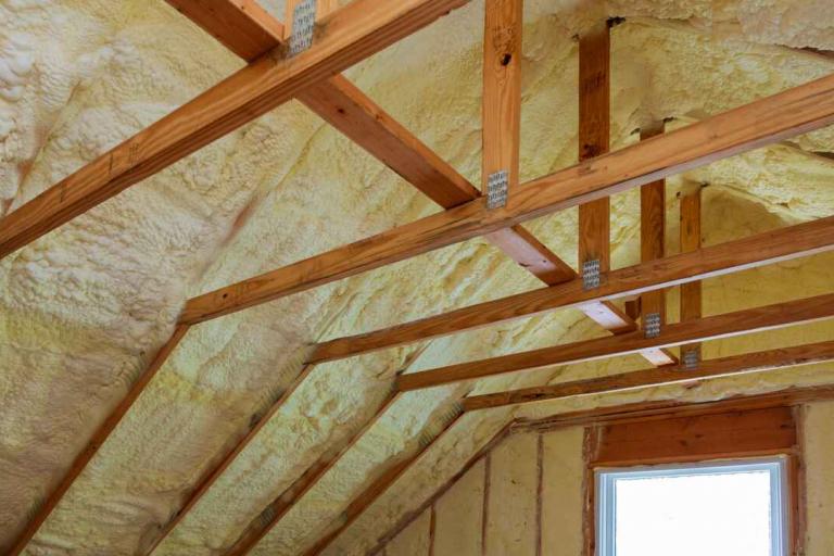 View of the inside of a loft space, with insulation foam between wooden joists