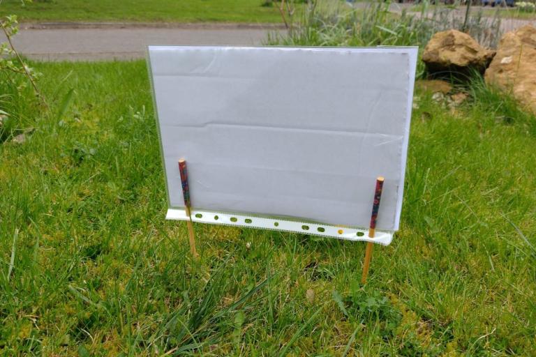 The sign planted in the grass. View from the back