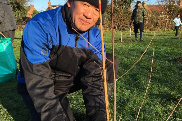 A man smiling planting a tree