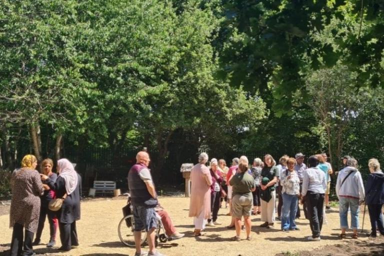 A group of people standing in a clearing between trees on a sunny day.