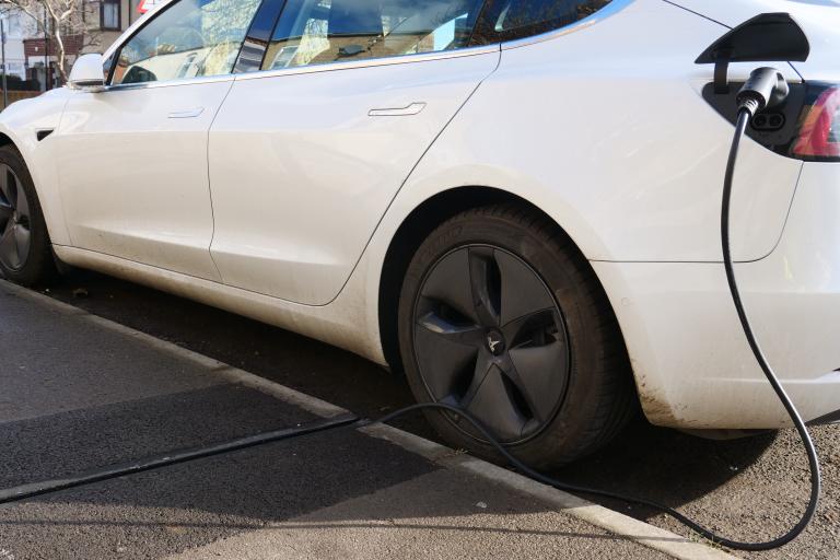 The Gul-e in use charging a white EV car at the side of a road.