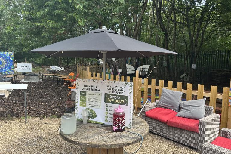A 'wellbeing garden' near a wooded area, containing sofas, parasols, tables, etc.